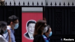 资料照:戴着口罩的上海市民走过内有一幅习近平画像的大门。(2020年5月22日)
