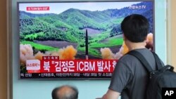 在首尔火车站,旅客观看关于朝鲜发射导弹的电视新闻(2017年7月4日)