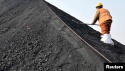 一名中国工人在山东日照港铲着从澳大利亚进口的煤炭。(资料照片)