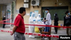 在新冠病毒疫情爆发最严重的湖北省武汉市,医护人员身穿防护服,在小区内对居民进行核酸检测(2020年5月15日)。