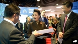 2015年10月21日,中国国家主席习近平夫妇访问伦敦帝国理工学院期间,中国第一夫人彭丽媛在接受赠送的礼物。(美联社照片)