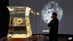 一位参观者正在中国国家博物馆观看嫦娥5号探月火箭2021年3月12号从月球采集到的新岩石样本。中国宣布他们在月球岩石中发现了一种新物质,取名叫“嫦娥石”。(美联社照片)