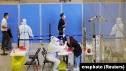 资料照:抵达上海虹桥国际机场的旅客在接受新冠核酸检测。 (2022年10月12日)