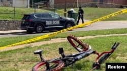 巴尔的摩一名警察走过枪击现场,路边有一辆儿童自行车。(2023年7月2日)