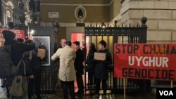 一群香港示威者在伦敦抗议香港经济质易办事处农历新年酒会,网名“揽炒巴"的香港民主派人士刘祖迪(图中手持抗议纸牌)2月13日傍晚带领示威者在市中心国宴厅外示威 (美国之音/郑乐捷)