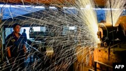 中国山东省青州市一个汽车轮辋工厂的工人正在生产线上工作。(2024年6月17日)