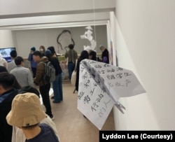 伦敦“白纸周年”艺术展上观众观看作品。(美国之音 李伯安)