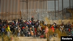 移民游过美墨边境的格兰德河后在边境隔离墙前聚集。(2023年12月18日)