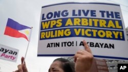 2024年7月12日,一名示威者在菲律宾奎松市举行集会时,举着标语和一面小菲律宾国旗,庆祝仲裁裁决宣布北京在南中国海领土主张无效 八周年。(美联社照片)