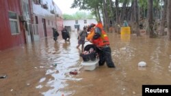 中国救援人员在房山县救助疏散受到洪水袭击的一名幼童。（2023年7月31日）