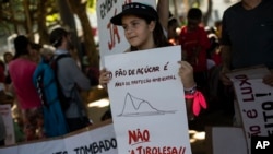 巴西一个孩子在里约热内卢举牌抗议在糖面包山修建新滑索。(2023年3月26日)