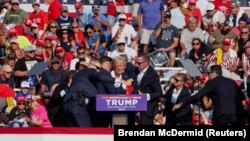 美国共和党总统候选人、美国前总统唐纳德·特朗普(Donald Trump)在宾夕法尼亚州巴特勒的竞选集会上被枪手击中右耳,随后美国特勤局人员将他搀扶起来。(2024年7月13日)
