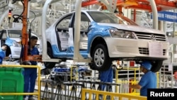 资料照片: 2018年9月4日中国新疆维吾尔自治区乌鲁木齐汽大众工厂员工组装汽车