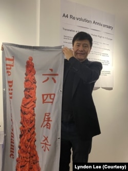 周锋锁在伦敦白纸运动展览上展示六四耻辱柱海报。(美国之音 李伯安)