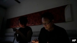资料照片:中国律师王全璋与妻子李文足在黑暗中查看手机,他们在北京的住所电力被当局切断(2023年6月20日)