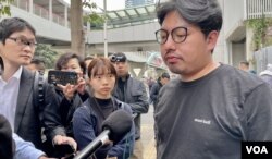 社民连内务副主席余炜彬接受传媒访问时,有便衣警察在后方近距离拍摄 (美国之音/汤惠芸)