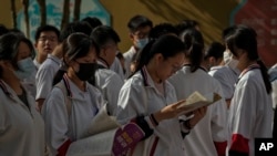 北京的中学生在进入高考考场前温习功课。(2023年6月7日)