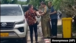 在这张由一位不愿透露姓名的消息人士拍摄的影片中,两名活动人士中的一位(左)与中国维权律师卢思位(右)同行,与拘留卢思位的警察发生争执,2023 年7月28 日 (匿名消息来源向美联社提供照片)