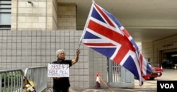 资料照片: 2023年11月29日社运人士王婆婆在西九龙裁判法院示威区内,独自一人手持英国旗及标语,要求释放47、释放所有政治犯 (美国之音/汤惠芸)