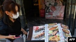 日本驻华大使馆附近的一家日本餐馆前一名女子在看餐馆菜单。(2023年8月29日)