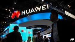 资料照片:在北京举行的 PT 博览会上,与会者走过中国技术公司华为的 5G 服务展示。(2019年10月31日)