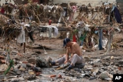 北京郊区遭洪水破坏村庄的一名男子在污水中清洗衣物。(2023年8月4日)