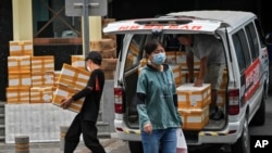 北京一家商业公司的工人正在从一辆小面包车上卸货。(2023年8月8日)