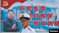 资料照:一名中国解放军海军士兵在香港的海军基地站在有着中国领导人习近平画像的宣传标语前。(2016年7月8日)
