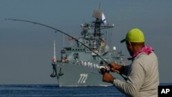 罗斯军舰自六月以来第二次例行访问古巴,哈瓦那一名钓客在岸边注视着俄罗斯的“不惧号”(Neustrashimy)巡逻舰。(美联社,2024年7月27日)