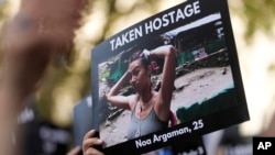 在伦敦的英国首相官邸唐宁街10号外举行支持以色列的集会上，一人手举一名25岁的以色列姑娘被巴勒斯坦武装分子劫为人质的照片。（2023年10月9日）