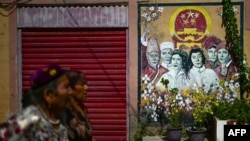 两名维吾尔妇女从喀什街道树立的政府宣传画前走过。(2023年7月14日)