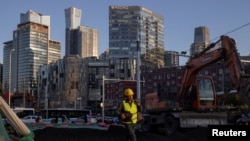 资料照片:一名工人走过北京商务中心区的一处建筑工地。(2023年2月28日)