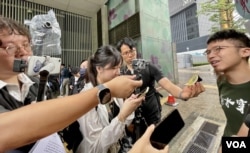 社民连外务副主席周嘉发(右一)表示,23条立法后在公众活动接受传媒访问时,警方的镜头(左上方以胶袋包裹)都会近距离拍摄,这种情况以往较少见(美国之音 照片)