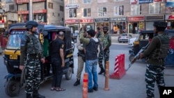 2023年5月20日,在印控克什米尔斯利那加举行的G-20旅游工作组会议之前,印度准军事士兵在临时检查站搜查一名克什米尔男子。(美联社照片)