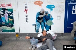 资料照：一名农民工在北京火车站的一个中国梦的政府宣传牌下打盹。