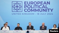 Britain's Prime Minister Keir Starmer speaks at the opening of the European Political Community meeting at Blenheim Palace in Woodstock, Britain, July 18, 2024. Seated to Starmer's left is Ukrainian President Volodymyr Zelenskyy.