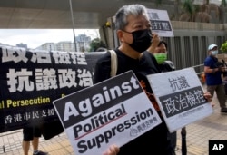 资料照:香港前“支联会”秘书长李卓人在他抵达香港一家法院前举牌抗议。(2021年4月1日)