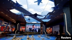 资料照片:北京的中国军事博物馆内在中国领导人习近平的巨幅电子屏幕前展示的军事装备模型。(2022年10月8日)