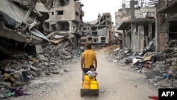 一名巴勒斯坦男子在加沙地带南部汗尤尼斯满是废墟的街道上拉着一辆手推车。（2024年5月2日）