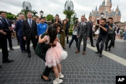 美国商务部长吉娜·雷蒙多在参观上海迪斯尼乐园期间拥抱一个身穿玲娜贝儿服装的中国小女孩。(2023年8月30日)