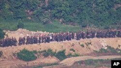 在韩国国防部2024年6月18日提供的这张未注明日期的照片中,从韩国警戒区可以看到朝鲜士兵在边境地区附近一个未公开的地点工作。