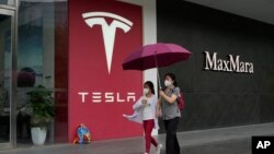 资料照:行人走过北京的一家特斯拉专卖店。(2023年5月31日)