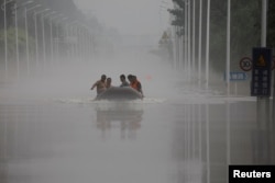 中国河北涿州民众在滔滔洪水中乘坐橡皮艇逃生。(2023年8月3日)