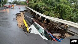 A vehicle is stuck in a collapsed section of road in Hong Kong on Sept. 8, 2023.