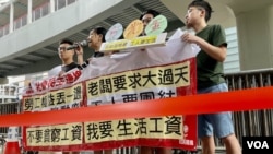 香港社民连4名成员,23条立法后首个五一劳动节到政府总部外请愿,在警方以红色胶带围封的示威区内拉横额及发言 (美国之音)