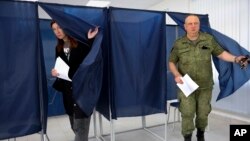 A woman and a serviceman leave a voting area at a polling station during Russia-organized elections in Donetsk, capital of Ukraine's mostly Russian-occupied Donetsk region, Sept. 10, 2023.