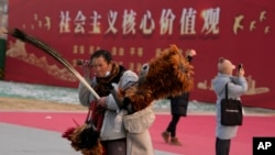 资料照:北京一名街头小贩走过“社会主义核心价值观”的宣传牌。(2024年1月20日)