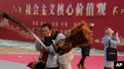 资料照:北京一名街头小贩走过“社会主义核心价值观”的宣传牌。(2024年1月20日)