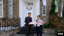 “29原则”执行总监叶七轮(Chakra Ip,右)代表85个人权组织将联署信递交老挝驻英国大使馆职员。(美国之音/郑乐捷)
