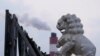 资料照 - 透过一座威严 的石狮雕像,可以看到上海附近的一座火力发电厂冒出的滚滚浓烟。照片来自路透社,拍摄时间是2021年10月21日。
